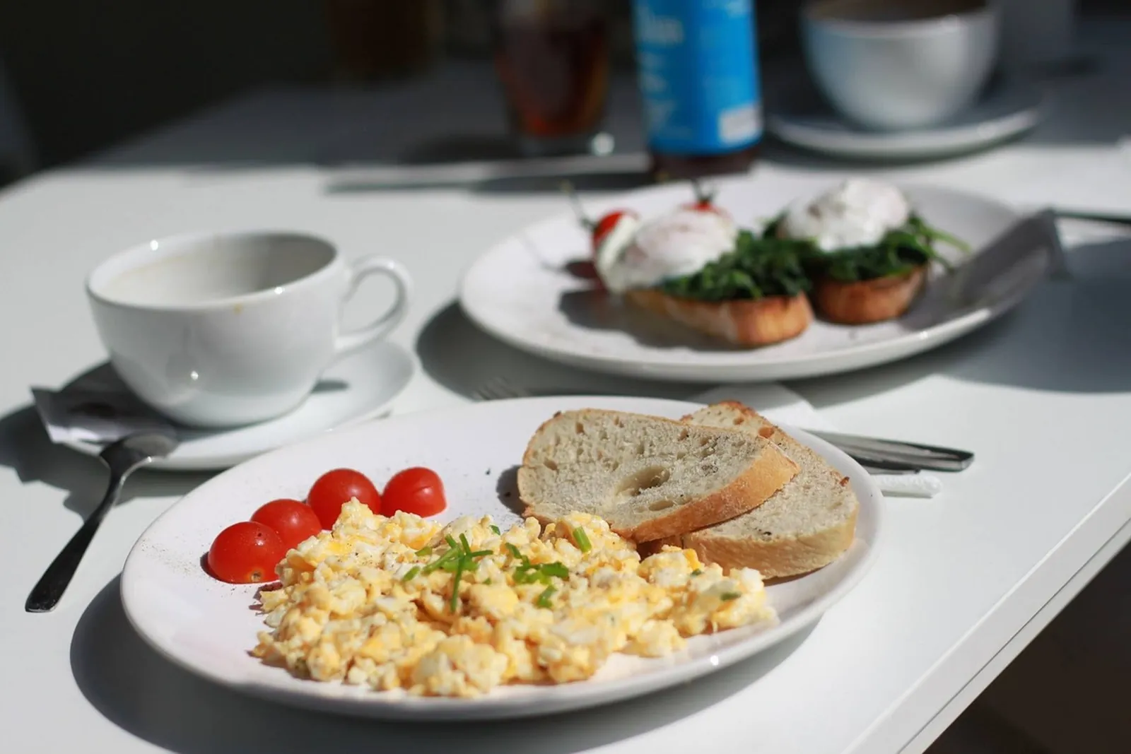 Scrambled eggs, toast, tomatoes and coffee on a white table